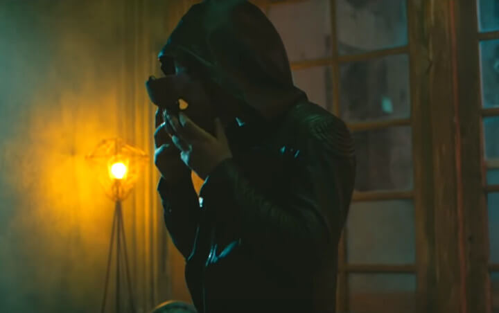 Potret karakter Gatotkaca yang mengenakan tudung hitam dan sedang memasang topengnya dalam teaser film